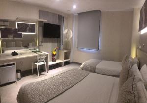 a hotel room with two beds and a desk at Hotel Perla Suite Santa Marta in Santa Marta +27 photos