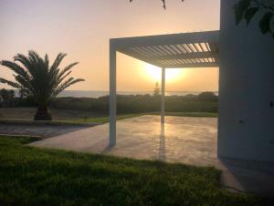 a pergola with the sun setting in the background at villa Lùmar fronte mare in Pachino