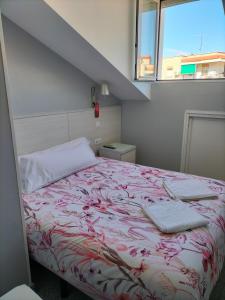 a bed with a red and white blanket and a window at Hostal San Pedro in Coslada