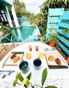 Ravine des Cabris的住宿－Chambres d'hôtes & spa Le Jardin de Ravintsara，一张桌子,上面有食物,放在游泳池边