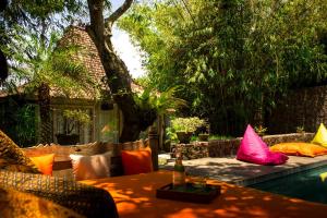 een tafel en stoelen met kleurrijke kussens op een patio bij Wahyu Private Lux Joglo Ideal For Couples W Pool in Seminyak