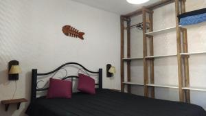 a bedroom with a black bed with pink pillows at Kavok in La Paloma