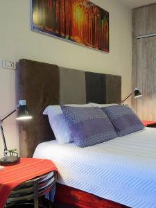 a bed with two pillows and a table with a lamp at Studio Mirador, todo lo que necesitas para disfrutar in Tarija