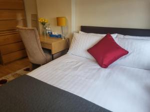 a bedroom with a white bed with a red pillow at Brooks Homestay in Dundalk