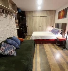 a bedroom with a bed and a couch with pillows at Studio Mirador, todo lo que necesitas para disfrutar in Tarija
