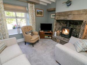a living room with a fireplace and a chair and a television at Moor Cottage in Carnforth