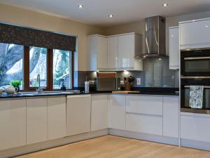 a large kitchen with white cabinets and windows at Golf View in Aboyne