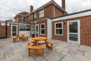 two picnic tables on a patio in front of a brick building at Modern and spacious 7 bedroom house in Littlehampton