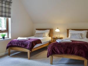 a bedroom with two beds with purple blankets at Golf View in Aboyne