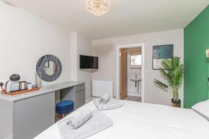 a white bedroom with a large bed and a bathroom at Modern and spacious 7 bedroom house in Littlehampton