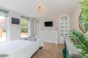 a white bedroom with a bed and a tv at Modern and spacious 7 bedroom house in Littlehampton