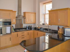 a kitchen with wooden cabinets and a black counter top at Apartment 8, The Bay in Torquay