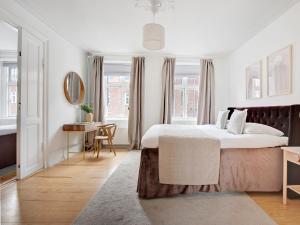 a white bedroom with a large bed and a desk at Sanders Stage - Chic Three-Bedroom Apartment Near Nyhavn in Copenhagen