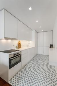 a kitchen with white cabinets and a tile floor at Casa Boma Lisboa - Design & Spacious Apartment With Balcony - Alvalade II in Lisbon