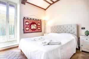 a bedroom with a bed with white sheets and a window at La Casa di Lalla in Sutri