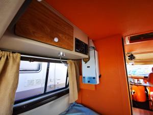 Habitación pequeña con pared de color naranja y ventana en Rent a BlueClassics 's Campervan combi J9 en Algarve au Portugal en Portimão