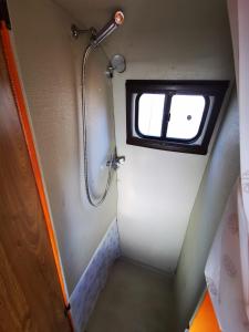 a small bathroom with a shower and a window at Rent a BlueClassics 's Campervan combi J9 en Algarve au Portugal in Portimão