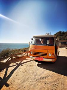 una furgoneta naranja estacionada en un camino de tierra junto al océano en Rent a BlueClassics 's Campervan combi J9 en Algarve au Portugal, en Portimão