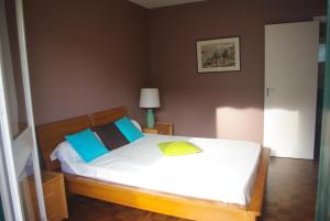 1 dormitorio con 1 cama con sábanas blancas y almohadas azules en Appartement Résidence du Lac, en San Juan de Luz