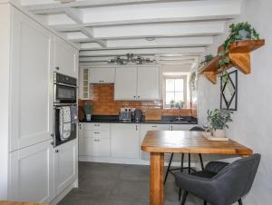 eine Küche mit weißen Schränken und einem Holztisch in der Unterkunft Lleiniog Cottage in Beaumaris