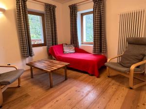 a living room with a red bed and a table at Casa Alfredino in Rocca Pietore