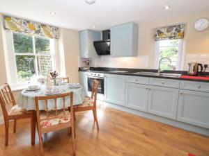 a kitchen with white cabinets and a table and chairs at South Wing Cottage in Yelverton