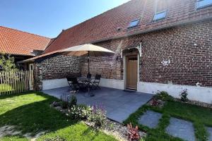 a patio with an umbrella in front of a brick house at La Cabarette in Arry