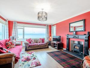 a living room with red walls and a fireplace at Cornerways in Blairmore