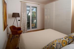1 dormitorio con 1 cama, 1 silla y 1 ventana en Appartamento coorte Brema, en Sirmione