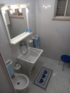 y baño con lavabo, aseo y espejo. en Casa Blu oltremare, en SantʼAntìoco