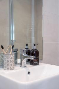 a bathroom sink with a bottle of soap and a mirror at No.192 Oxford in Oxford