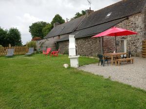 a table with a red umbrella next to a building at Les Gîtes du Triskell, gîte du Feu in Sainte-Tréphine