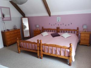 a bedroom with a large wooden bed and two dressers at Les Gîtes du Triskell, gîte du Feu in Sainte-Tréphine