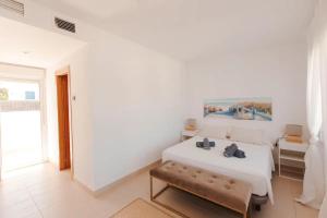 Dormitorio blanco con cama y banco en Villa Marejada 19, en San José 16 fotos más