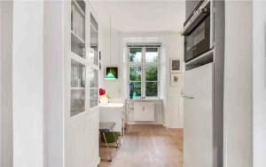 a white kitchen with a table and a refrigerator at The heart of Copenhagen-Queen's Neighbor in Copenhagen