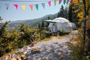 a yurt in a forest with a tent and flags at Ajara Glamping Kokotauri in Keda