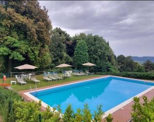 une grande piscine avec des chaises et des parasols dans l'établissement Casa Vacanze "L'Aione", à Gambassi Terme