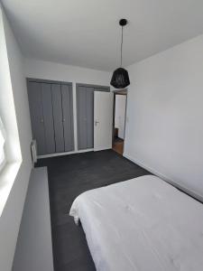 a bedroom with a white bed and a black lamp at Le Sarcoui - Appartement tout confort proche de la Gare in Clermont-Ferrand