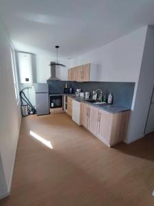 a large kitchen with wooden cabinets in a room at Le Sarcoui - Appartement tout confort proche de la Gare in Clermont-Ferrand