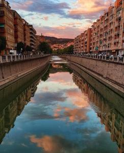 un río en una ciudad con edificios y reflejos en el agua en Apartamento Ronda Genil con parking gratuito, en Granada
