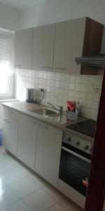 a white kitchen with a sink and a stove at Apartmani kod Rade in Pakoštane