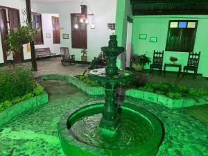 a green fountain in the middle of a courtyard at Hotel Casa Antigua Buga in Buga