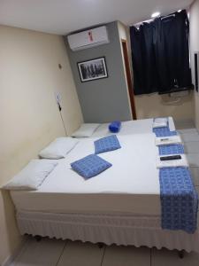 Bett in einem Zimmer mit blauen Kissen darauf in der Unterkunft Hotel Kairos in Campina Grande