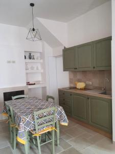 eine Küche mit einem Tisch und grünen Schränken in der Unterkunft A Due Passi dal Centro - Monte Grappa in Alberobello