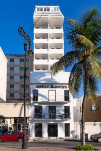 a white building with a palm tree in front of it at Hawaii Hotel Veracruz in Veracruz