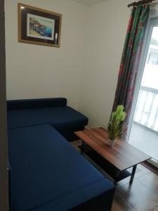 a living room with a blue couch and a table at Apartmani kod Rade in Pakoštane