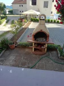 a brick patio with a pizza oven with a hose at Apartmani kod Rade in Pakoštane