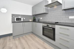 una cocina con armarios blancos y electrodomésticos negros en Townhouse @ Bedford Street Crewe en Crewe