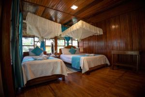 two beds in a room with wooden walls and wood floors at Yarina Eco Lodge in Derna