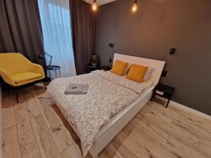 a bedroom with a bed and a yellow chair at Tesorio Apartment - AC, Free Parking, WiFi, Business & Family in Wrocław